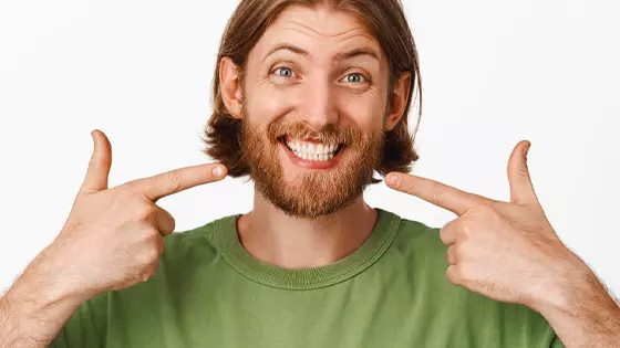 homem sorrindo apontando para os dentes